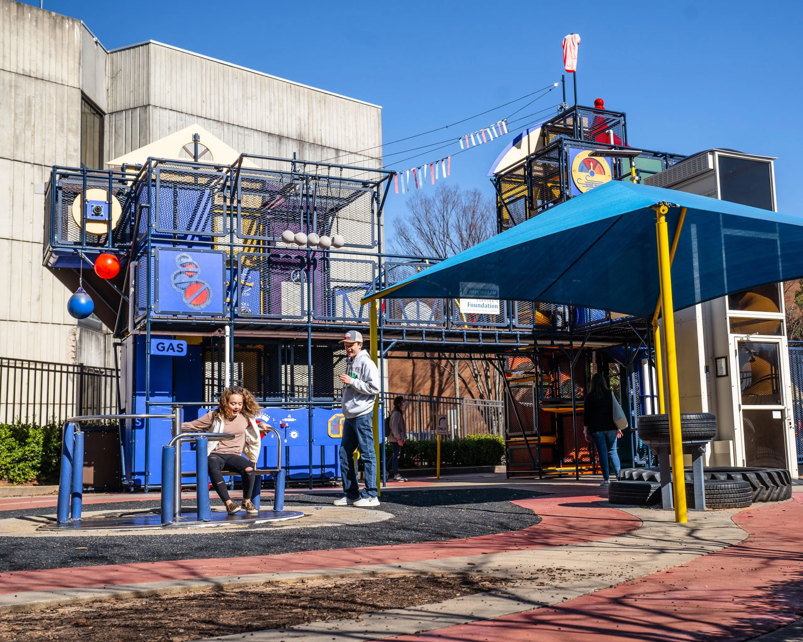 Two kids playing on Bib's World, the outdoor playground exhibit at the Children's Museum of the Upstate Greenville location.