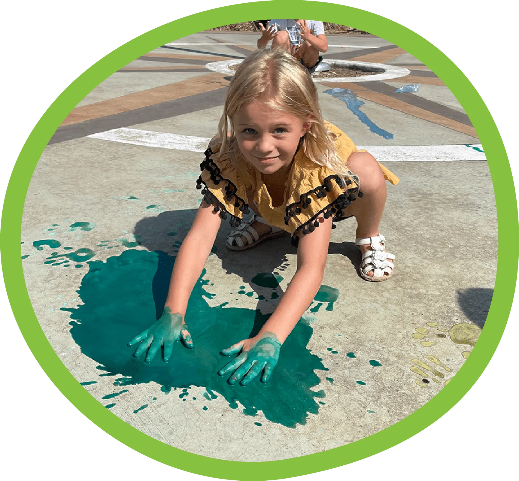 Girl playing with paint outside on the sidewalk outside the Children's Museum of the Upstate Greenville location.