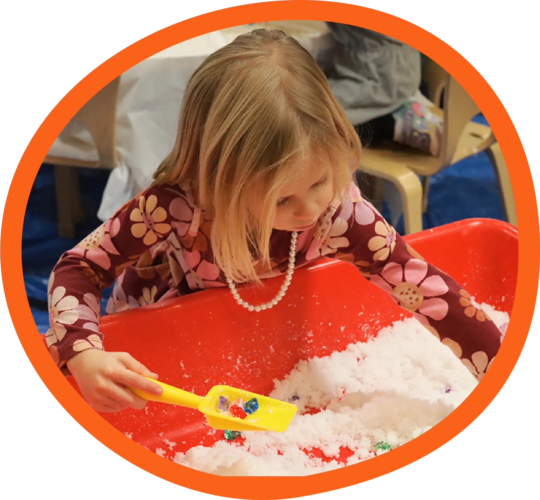 Girl playing with gems and fake snow in a bucket at the Children's Museum of the Upstate Greenville location.