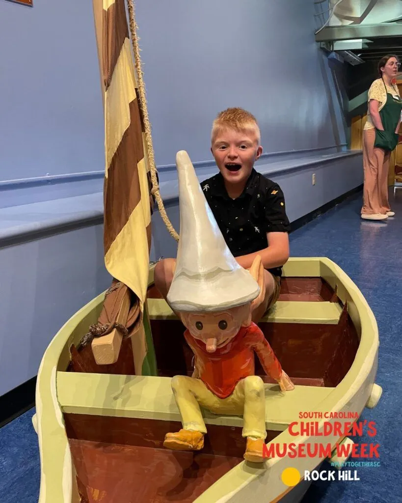 a young boy in a toy boat with a flag