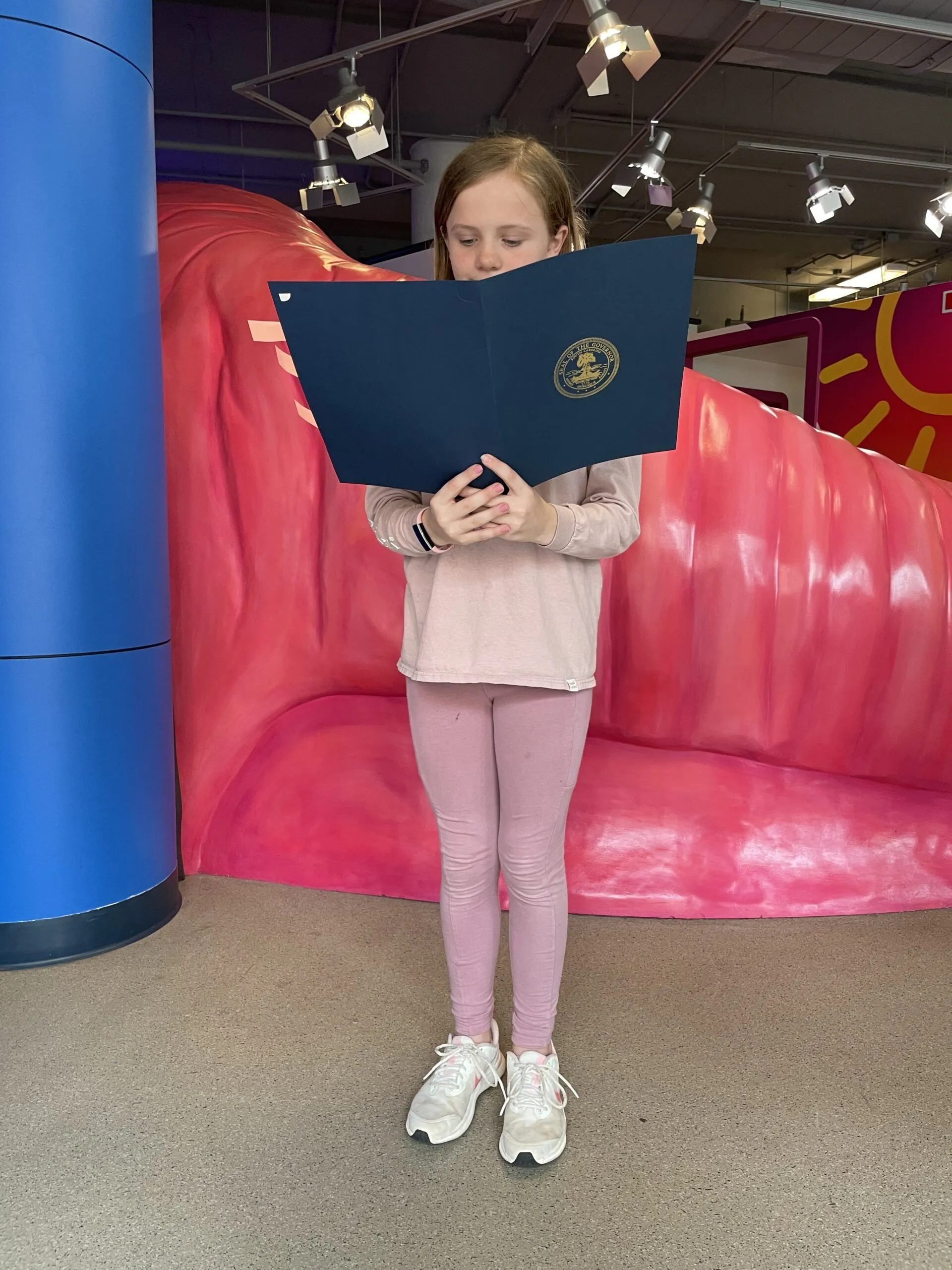 Child holding notebook outside the health exhibit at the Children's Museum of the Upstate Greenville location.