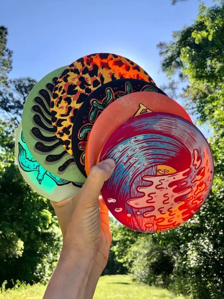 a person holding three frisbees in their hand