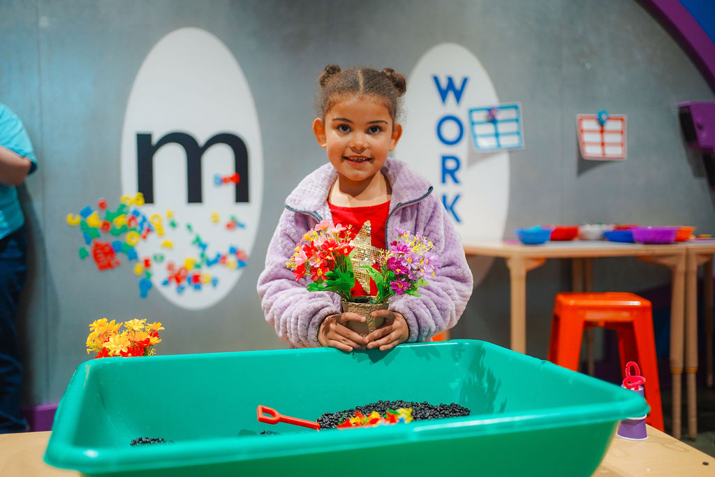 a young girl holding a potted plant in front of a table