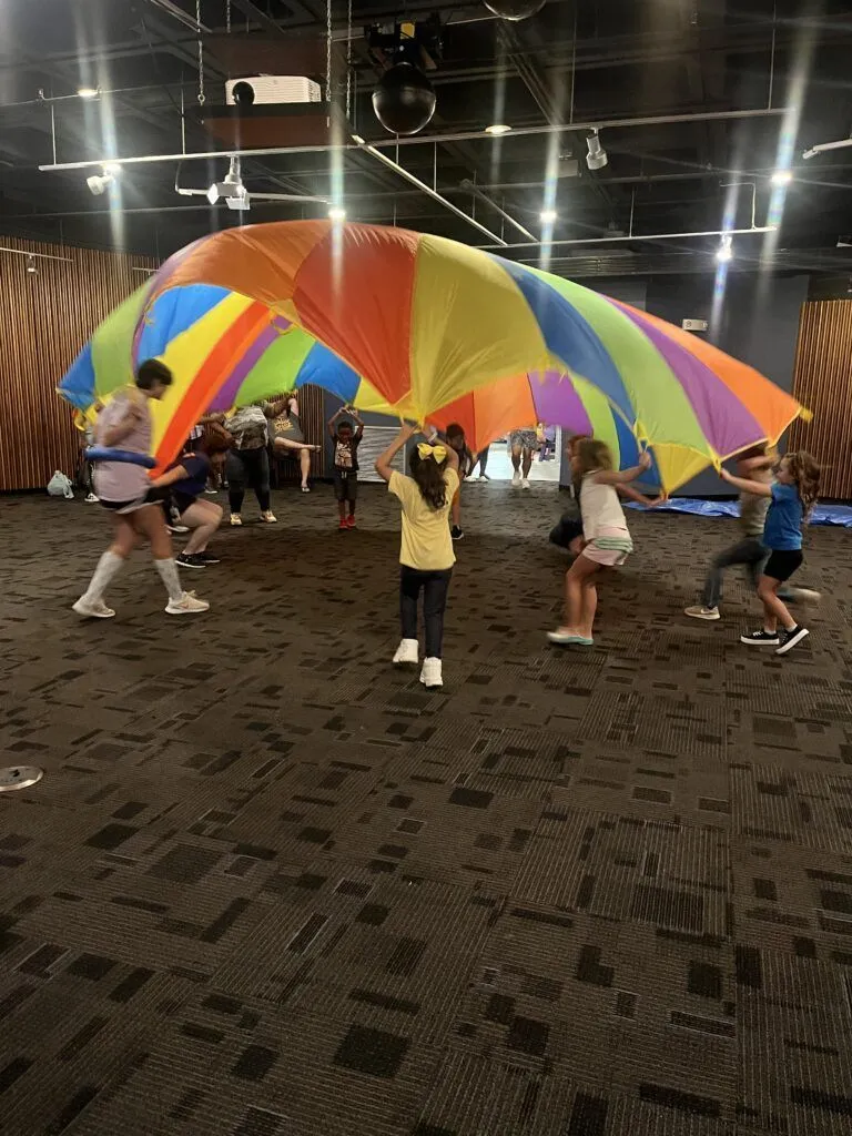 a group of people standing around a colorful umbrella