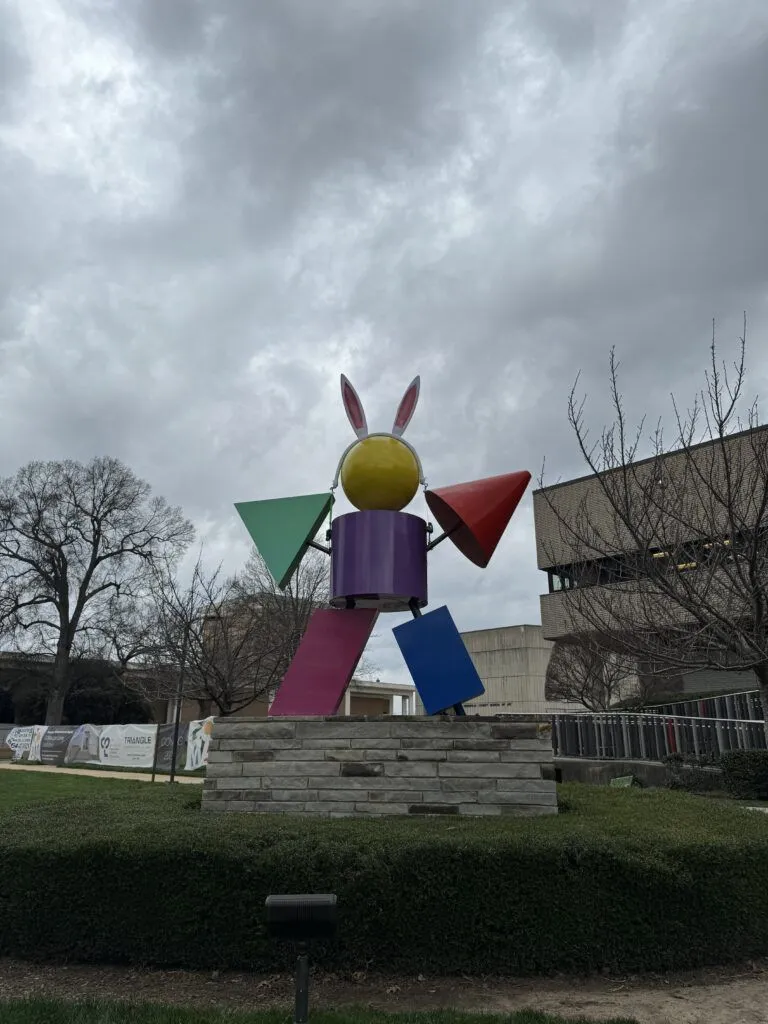 a sculpture in a park with a building in the background
