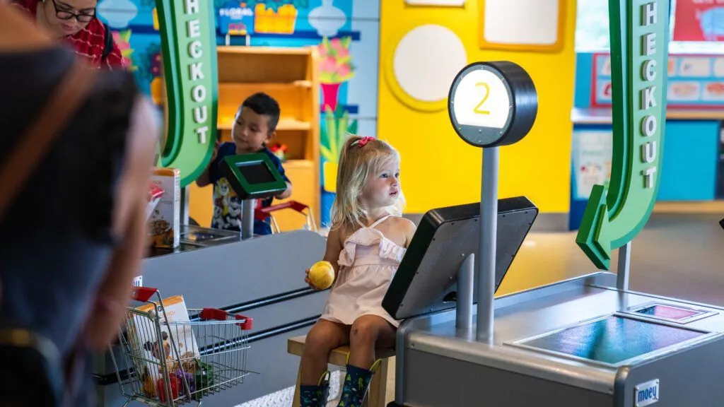 a little girl sitting on a bench in a toy store