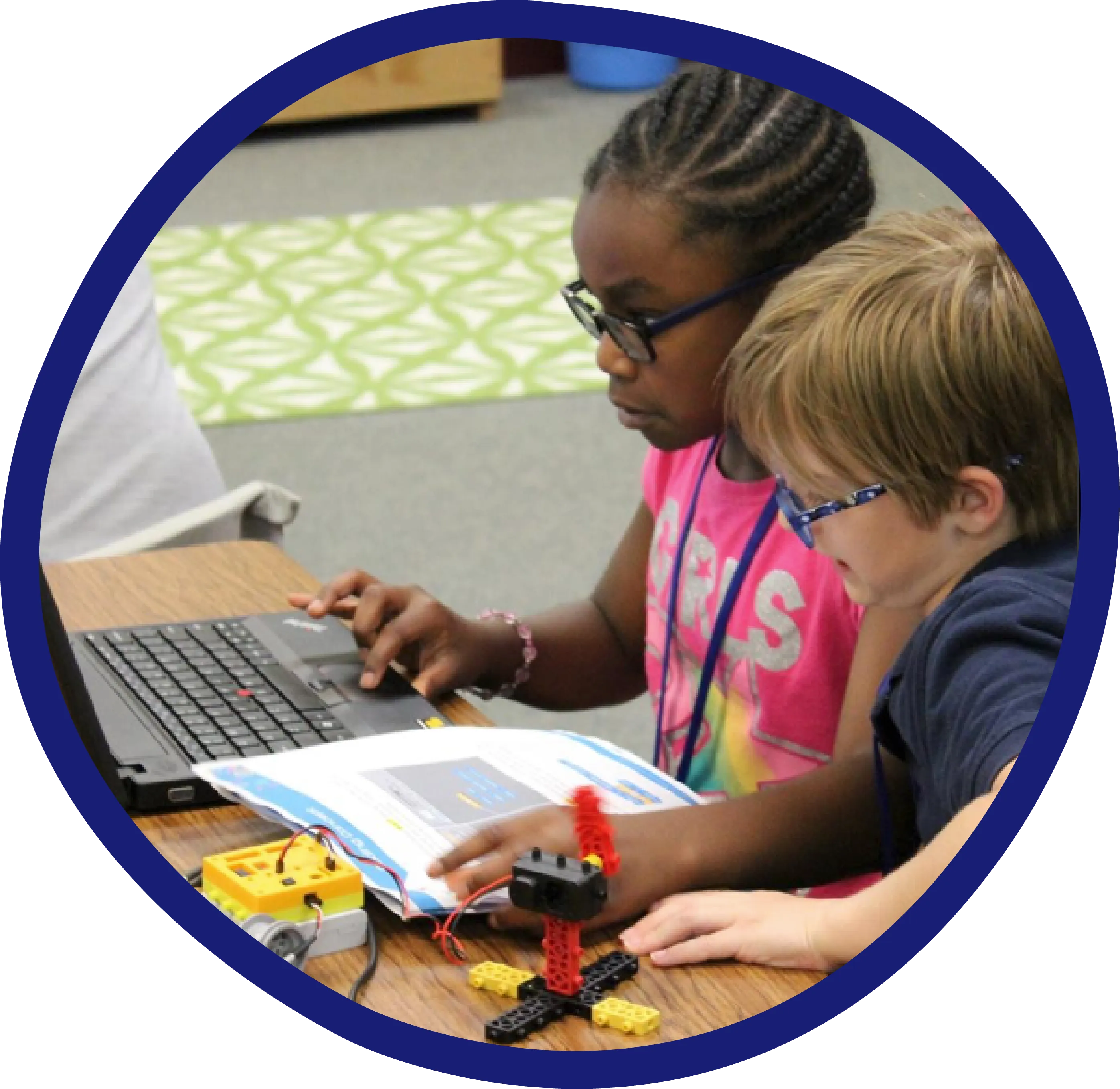 a couple of kids sitting in front of a laptop computer