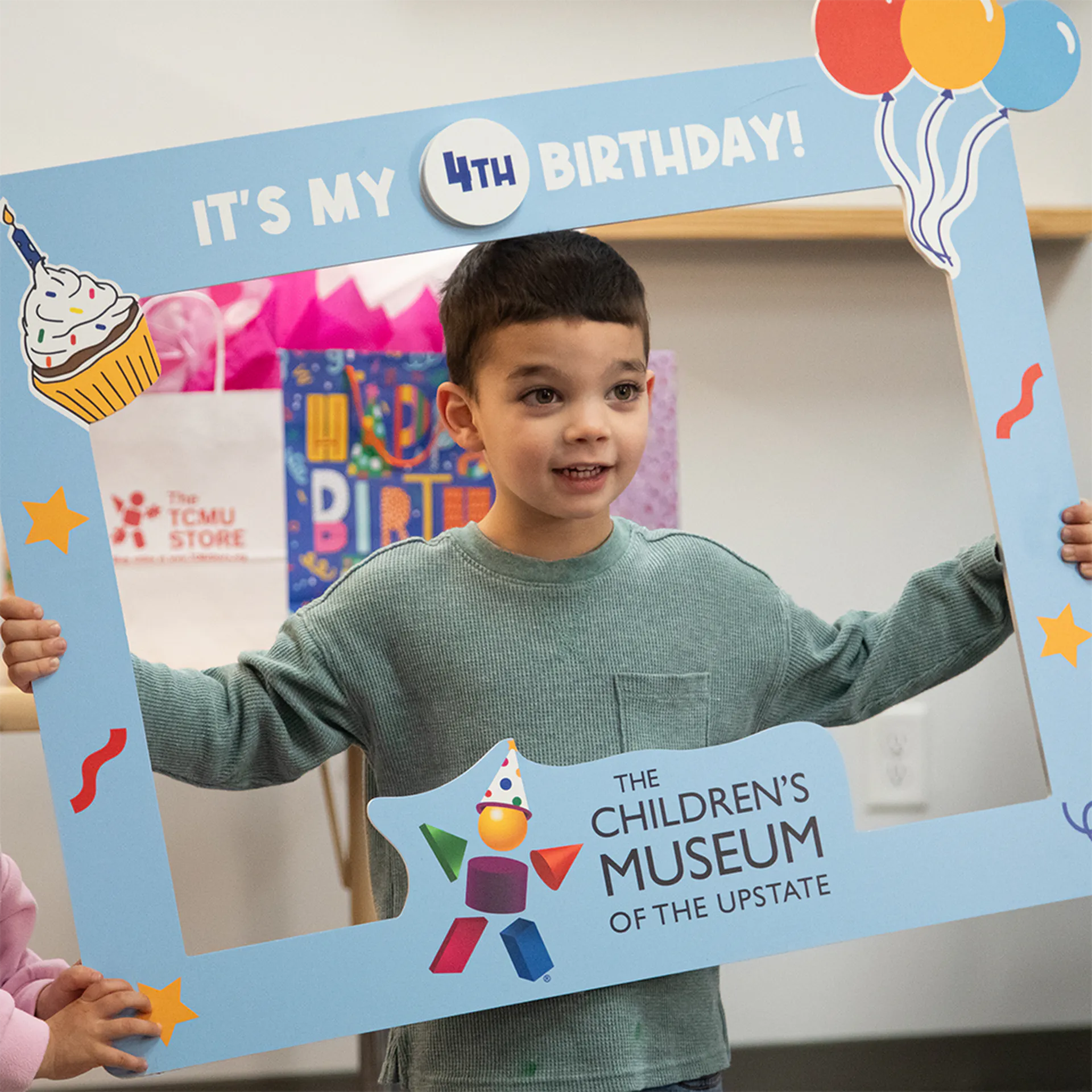 Kid holding a sign-frame that says "It's by 4th Birthday" around his head.
