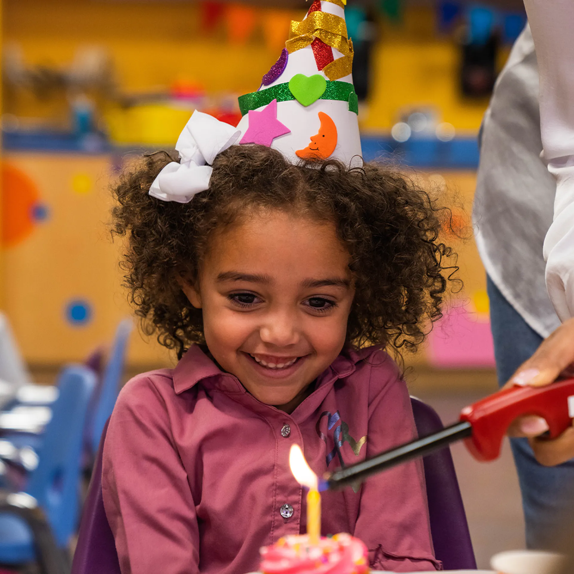 Birthday girl getting the candle on her cupcake lit by her mom at the Children's Museum of the Upstate Greenville location.