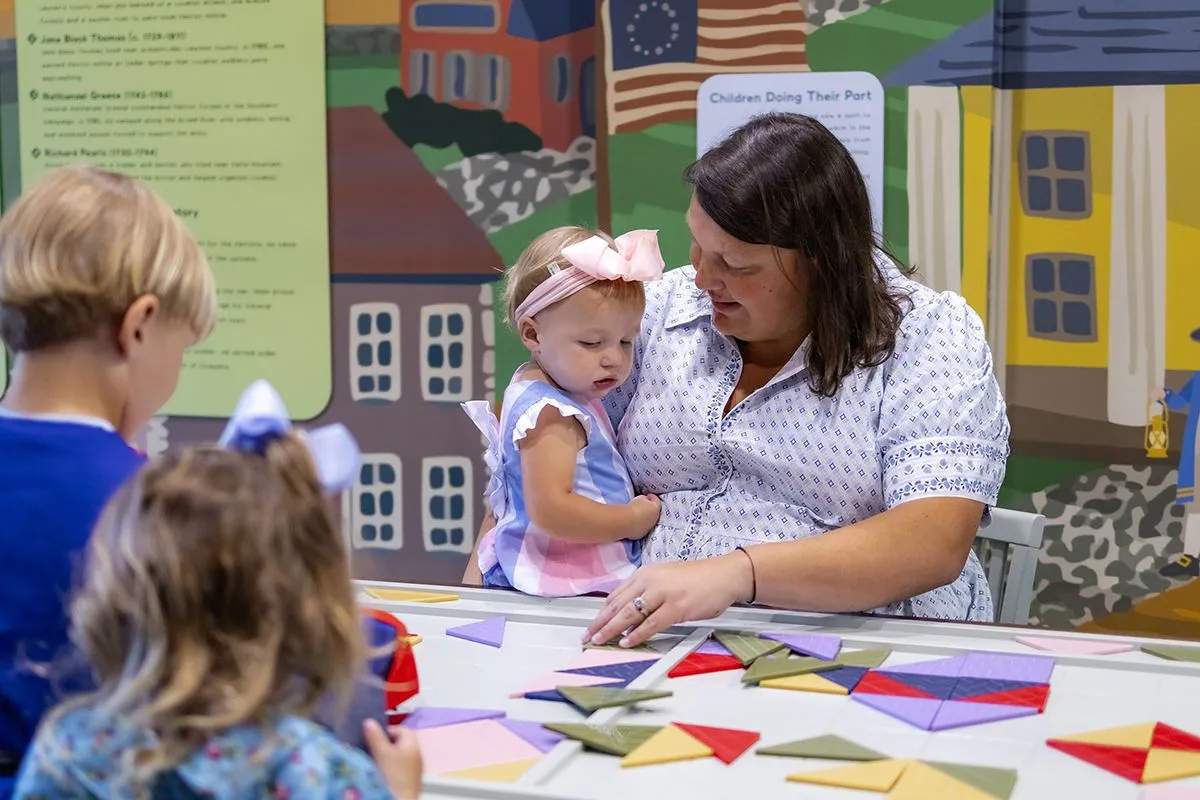 mother holding daughter and playing with quilt tiles and designs in TCMU 1776