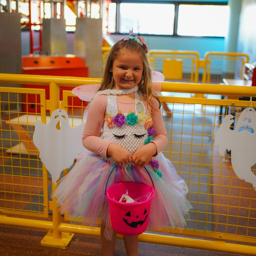 a little girl in a costume holding a bucket