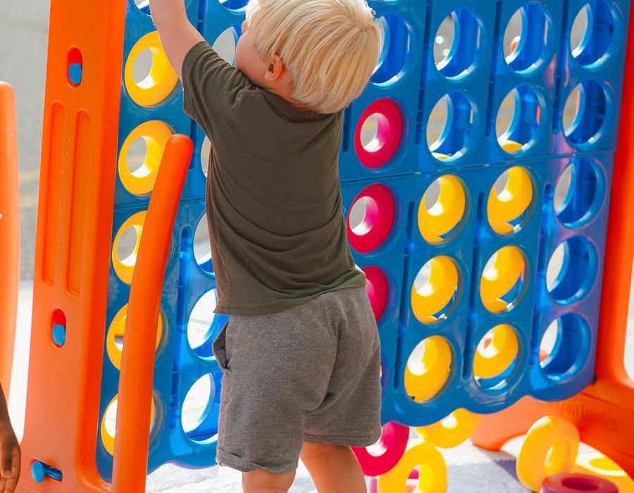 child puts a yellow connect 4 piece into a lifesize game