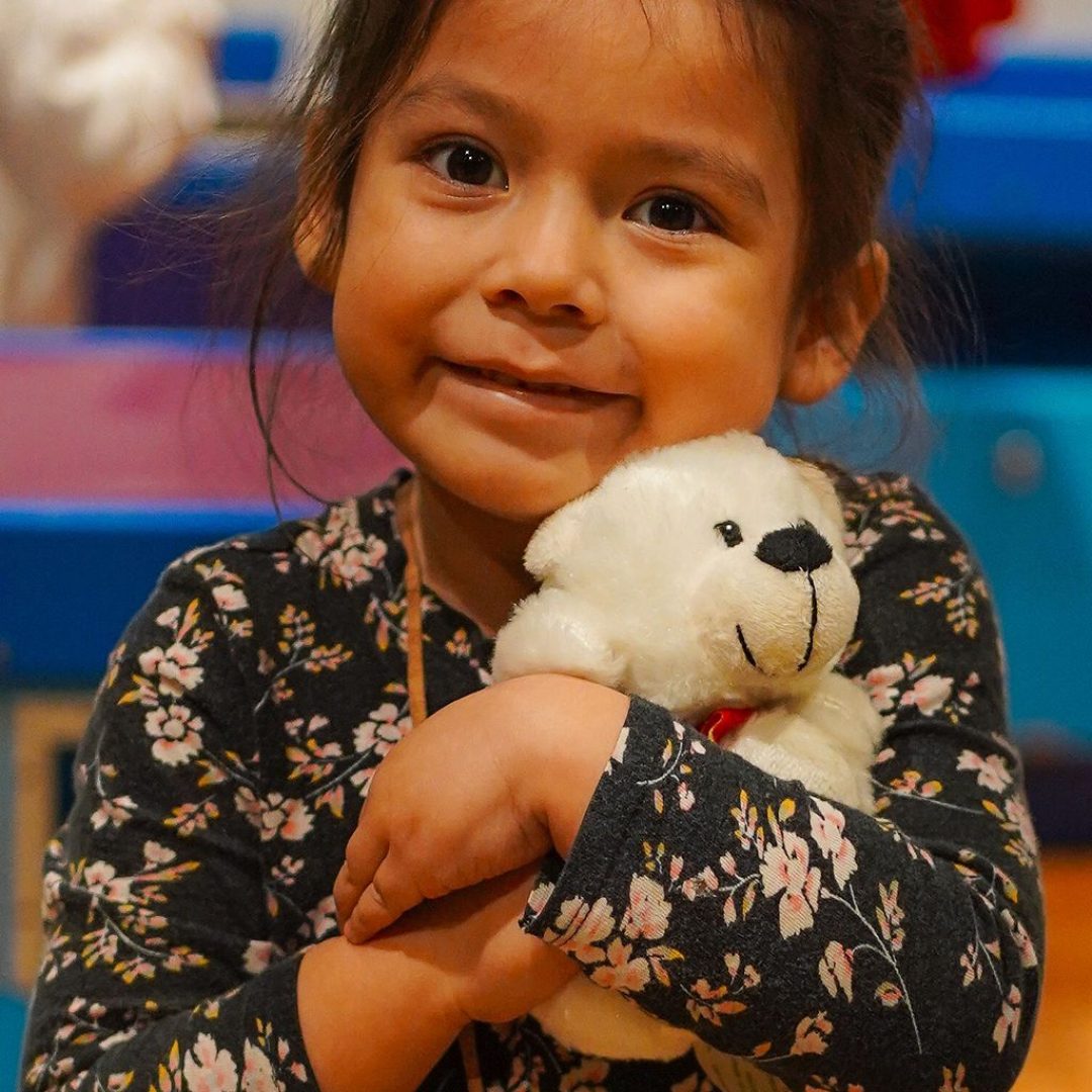 a little girl holding a teddy bear in her arms